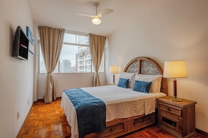 A hotel room with a bed, two bedside lamps, a TV mounted on the wall, and a window with curtains. - Stylish & Charming in Consolação/Higienópolis • Parking • 3rd Guest Free (Sao Paulo)