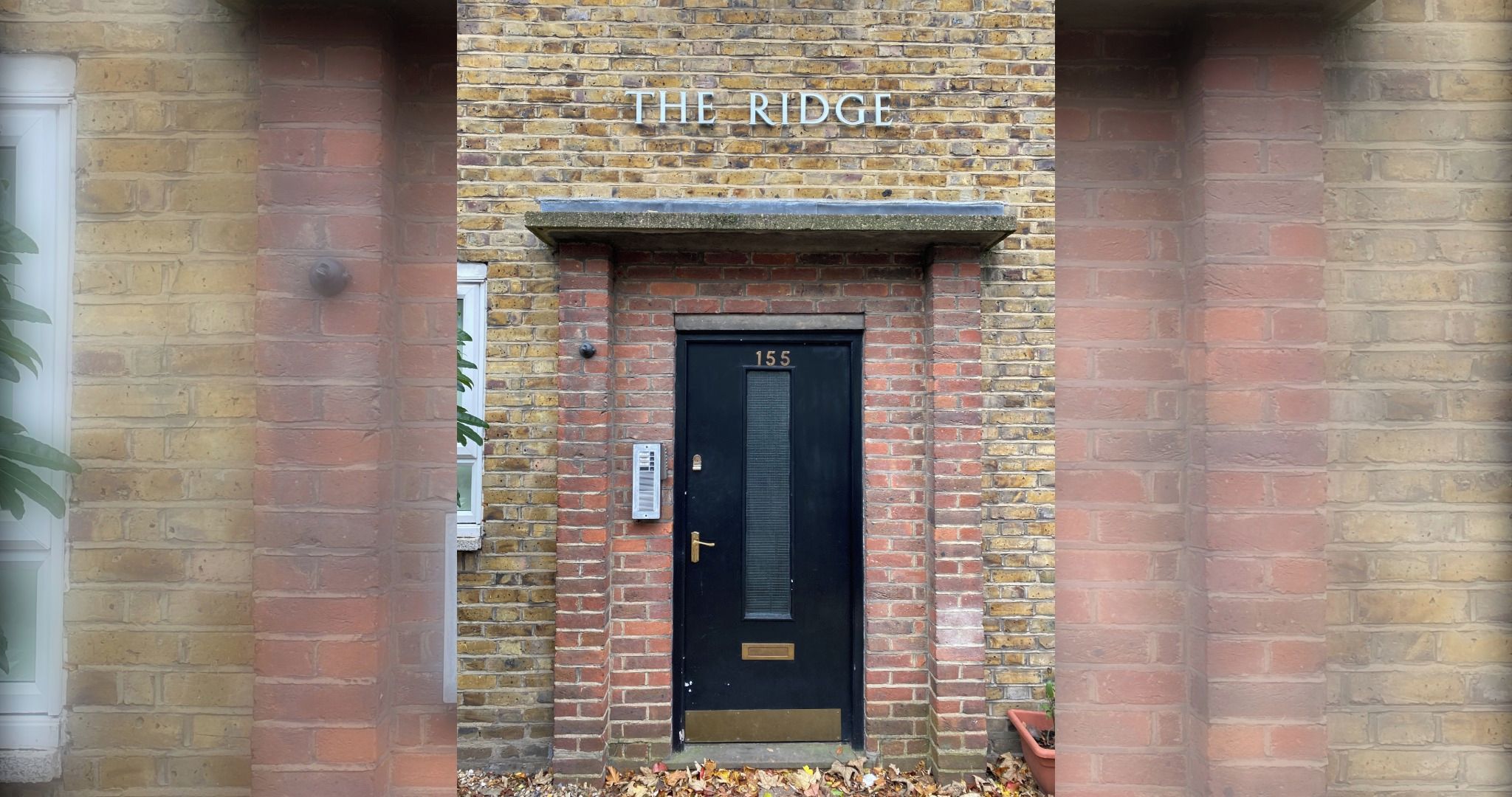 A brick building with a black door labeled 'THE RIDGE' and the number '155' above it.