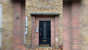 A brick building with a black door labeled 'THE RIDGE' and the number '155' above it. - Spacious & Central | 1 Bed | WiFi | Regent's Canal (London)