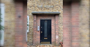A brick building with a black door labeled 'THE RIDGE' and the number '155' above it.