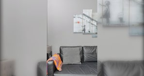 A modern living room with a grey sofa, a colorful throw blanket, and abstract wall art. - Spacious & Central | 1 Bed | WiFi | Regent's Canal (London)