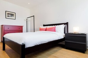 A modern bedroom with a bed, a nightstand, a dresser, and a framed picture on the wall. - Bright and Charming 4BD Family Haven in Kennington (London)