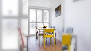 A dining area with a table, chairs, and a window with a view of buildings.