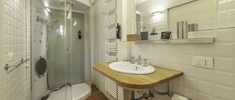 A modern bathroom with a glass-enclosed shower, a wooden vanity with a sink, and a mirror above the sink.
