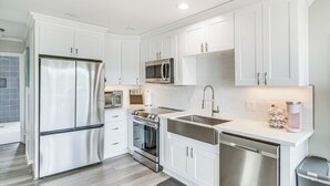 A modern kitchen with white cabinetry, stainless steel appliances, a microwave, oven, and a dishwasher. - Bay St Louis Home w/ Private Dock + Kayaks! (Bay St Louis)