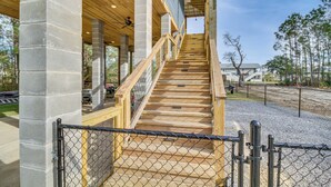 A wooden staircase with a metal fence in front, leading to a covered area with a ceiling fan. - Bay St Louis Home w/ Private Dock + Kayaks! (Bay St Louis)