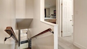 A staircase with a handrail, a door, and a window with a view of a bedroom. - Luxury Old Town 2BR/2BA • AC • 2 Pools • Parking (Scottsdale)