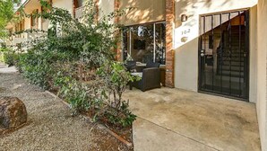 A building with a number 102 on the wall, a gated entrance, and outdoor seating. - Luxury Old Town 2BR/2BA • AC • 2 Pools • Parking (Scottsdale)