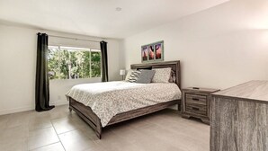 A bedroom with a bed, a nightstand, a dresser, a window with curtains, and a wall-mounted picture. - Luxury Old Town 2BR/2BA • AC • 2 Pools • Parking (Scottsdale)