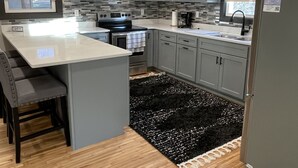 Une cuisine moderne avec des meubles gris, un îlot central, un four à micro-ondes, une cuisinière et un réfrigérateur.