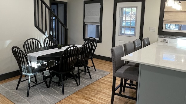 Une cuisine moderne dotée d’un grand îlot central, de chaises en bois foncé et d’un escalier menant à un autre niveau.