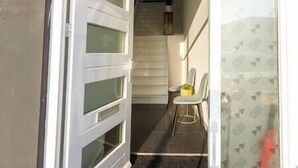 A hallway with a staircase leading to an upper floor, a dining area with a table and chairs, and a patterned curtain. - Spacious private apartment, 90m2, 25min from Amsterdam (Hilversum)