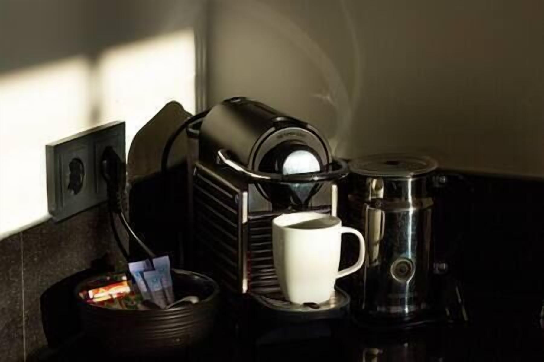A coffee machine with a cup and a thermos on a counter.