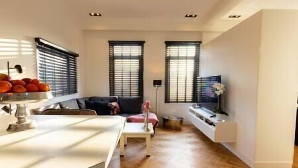 A modern living room with a sofa, a dining table, and a TV on a stand. - Spacious private apartment, 90m2, 25min from Amsterdam (Hilversum)
