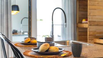 A modern kitchen with a granite countertop, a stainless steel faucet, and a wooden shelf.