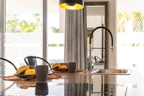 A modern kitchen with a stainless steel sink, a black faucet, and a pendant light.