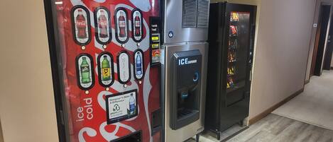 Máquina expendedora con publicidad de Coca-Cola y dispensador de hielo.