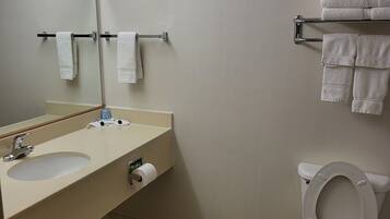A bathroom with a sink, mirror, towel rack, toilet, and a toilet paper holder.