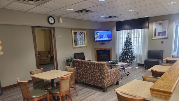 Un hall d’hôtel avec une cheminée, un sapin de Noël et un téléviseur diffusant un programme d’information.