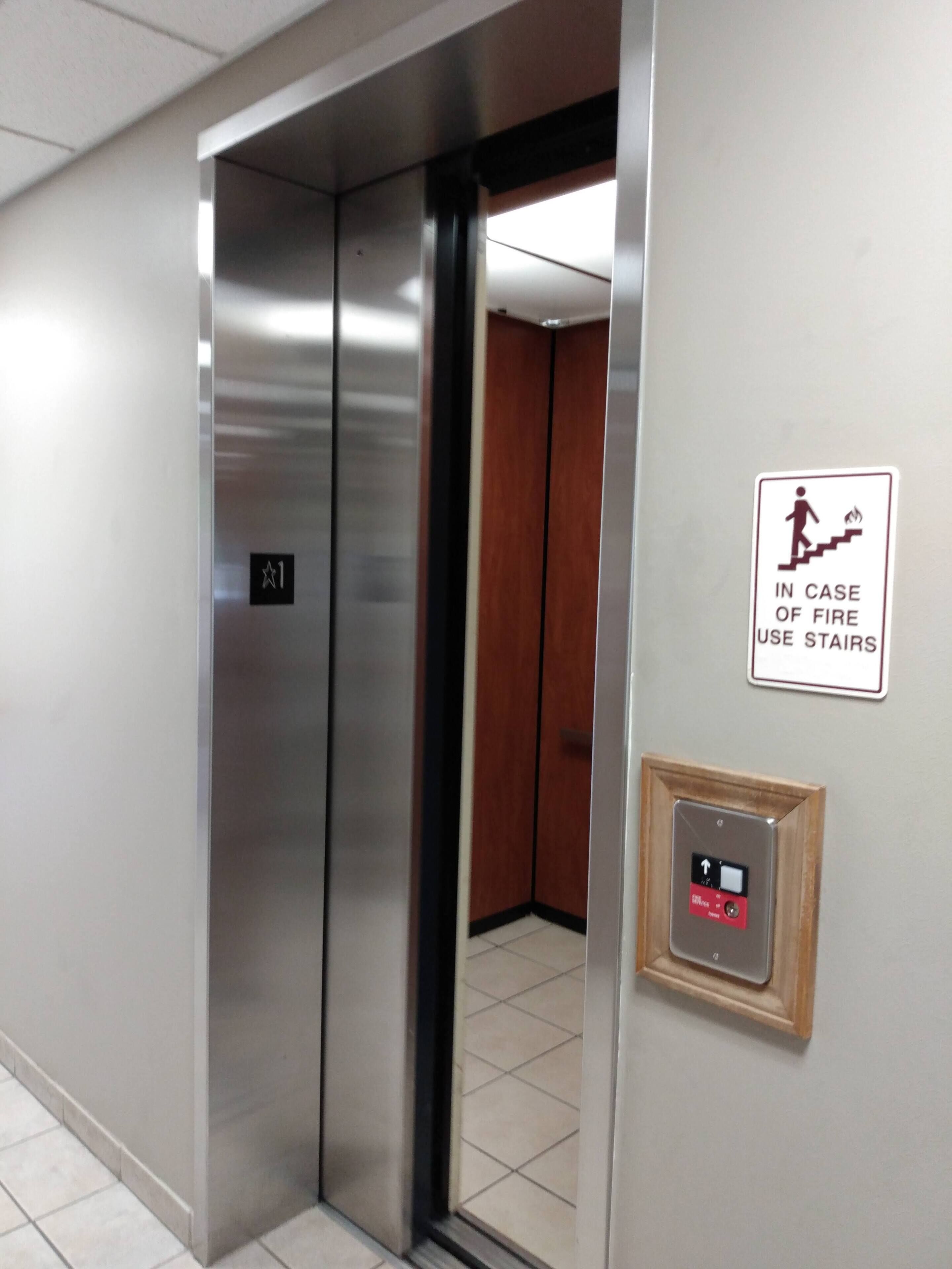 An elevator with a digital display, a fire safety sign, and a door number.