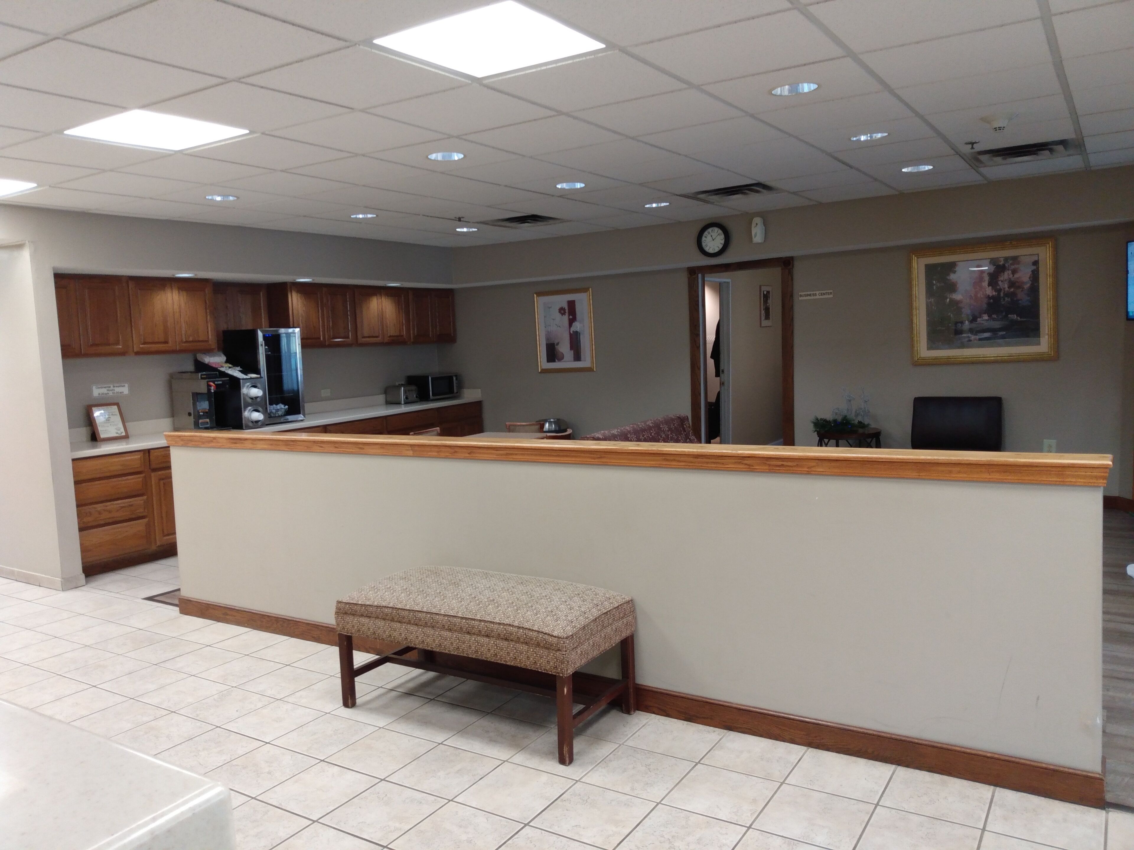Un área de recepción con un mostrador de madera, un banco y un reloj en la pared.