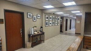 Un couloir avec des tableaux encadrés accrochés au mur, un banc en bois et une poubelle.