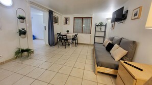 Una sala de estar moderna con un sofá, televisor y comedor con mesa y sillas.