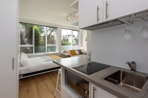 A compact kitchen with a built-in oven, a sink, and a window overlooking a garden.