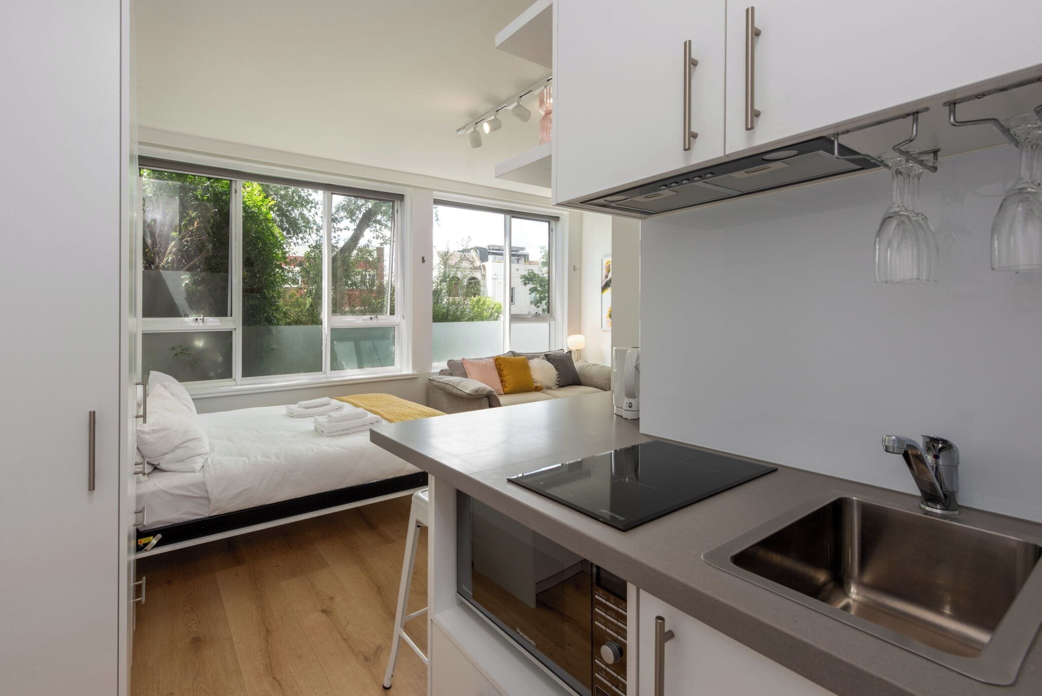 A compact kitchen with a built-in oven, a sink, and a window overlooking a garden.