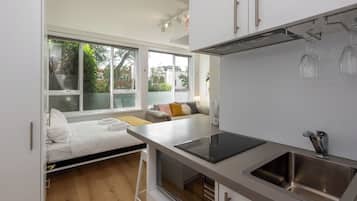 A compact kitchen with a built-in oven, a sink, and a window overlooking a garden.