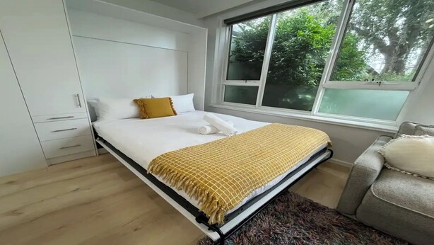 Une chambre à coucher avec un lit, une fenêtre, une armoire et une chaise.