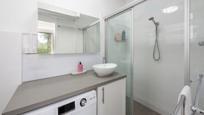 A modern bathroom with a white sink, a glass shower enclosure, and a built-in dishwasher. - Lovely Studio with Free Parking in East Melbourne! (East Melbourne)