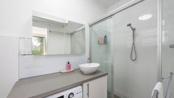 A modern bathroom with a white sink, a glass shower enclosure, and a built-in dishwasher.