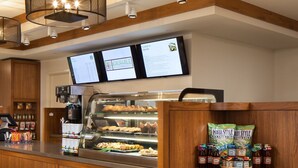 A bakery counter with a coffee machine, menu boards, and a display of baked goods.