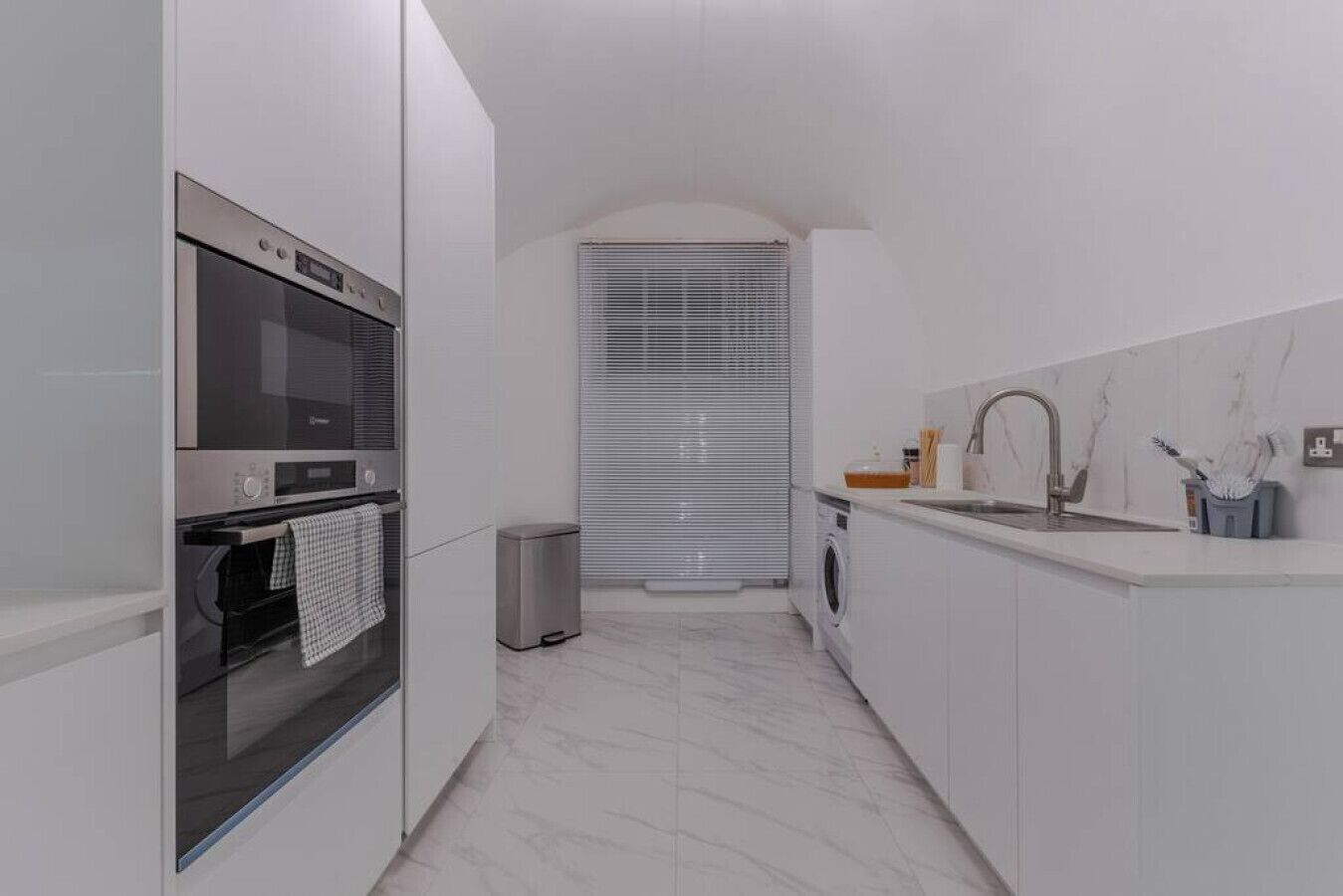 Une cuisine moderne équipée d’un four encastré, d’un lave-linge et d’un évier.