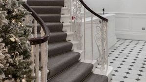 A staircase with a white railing and grey steps, leading to a landing with a white wall and a pink decorative element. - Luxurious 1 Bedroom on Iconic Harley Street (Greater London)