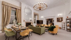 A spacious living room with a dining area, a fireplace, a television, and a chandelier. - Luxury London 3-Bedroom Duplex with Pool Table (Greater London)