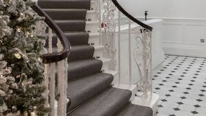 A staircase with a white railing and grey steps, leading to a landing with a white wall and a pink decorative element. - Modern Elegance: 1-Bedroom City Living in London (Greater London)