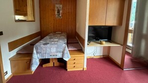 A compact bedroom with a bed, a small desk, and a television.