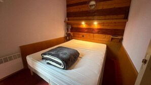 A small, cozy room with a wooden headboard, a single bed, and a small bedside table.