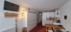 A compact kitchen with a refrigerator, microwave, and wooden table.