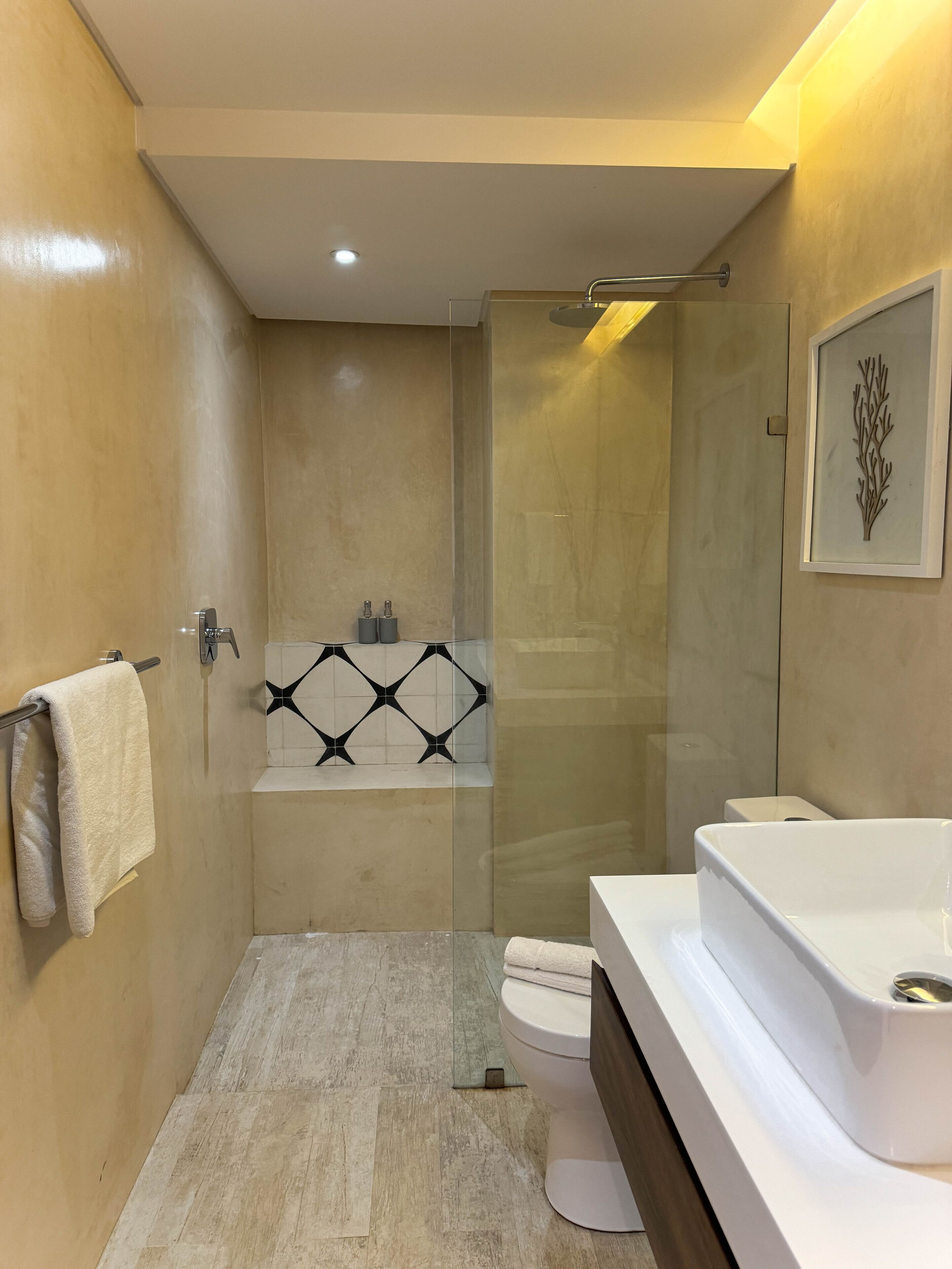 A modern bathroom with a glass-enclosed shower, a white bathtub, and a large white sink.