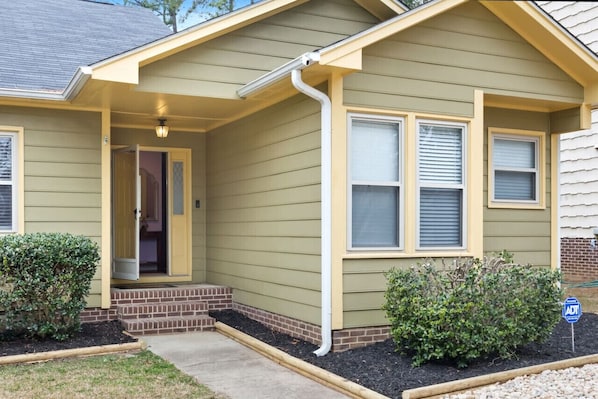 A house with a front porch, a garage door, and a small garden area.