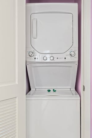 A white stacked washer and dryer unit with control knobs and a door.