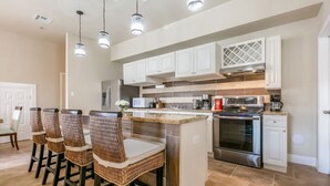 Una cucina moderna con isola centrale, elettrodomestici in acciaio inossidabile e zona pranzo con sedie in vimini.