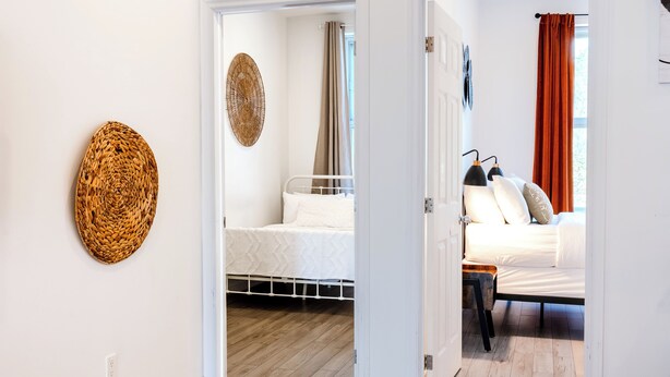 A room with a bed, a bedside table, and a wall-mounted woven basket. - Unique Stays - 3658 Boul. Saint-Laurent (Montreal)