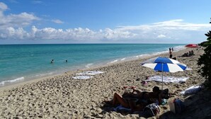 Una playa con sombrillas, gente y el océano.