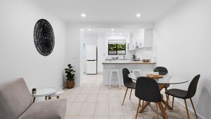 Una cocina moderna con armarios blancos, una isla central y vistas al exterior.