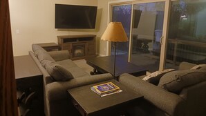 A living room with a sofa, a coffee table, a fireplace, and a television.