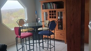 A dining area with a round table, four chairs, and a wooden cabinet with books.
